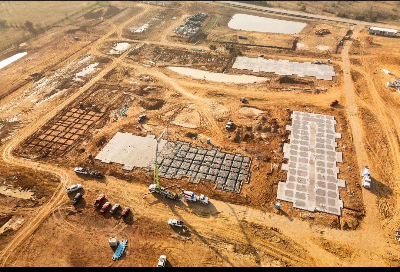 Aerial view of multiple foundation areas and construction activity across a development site