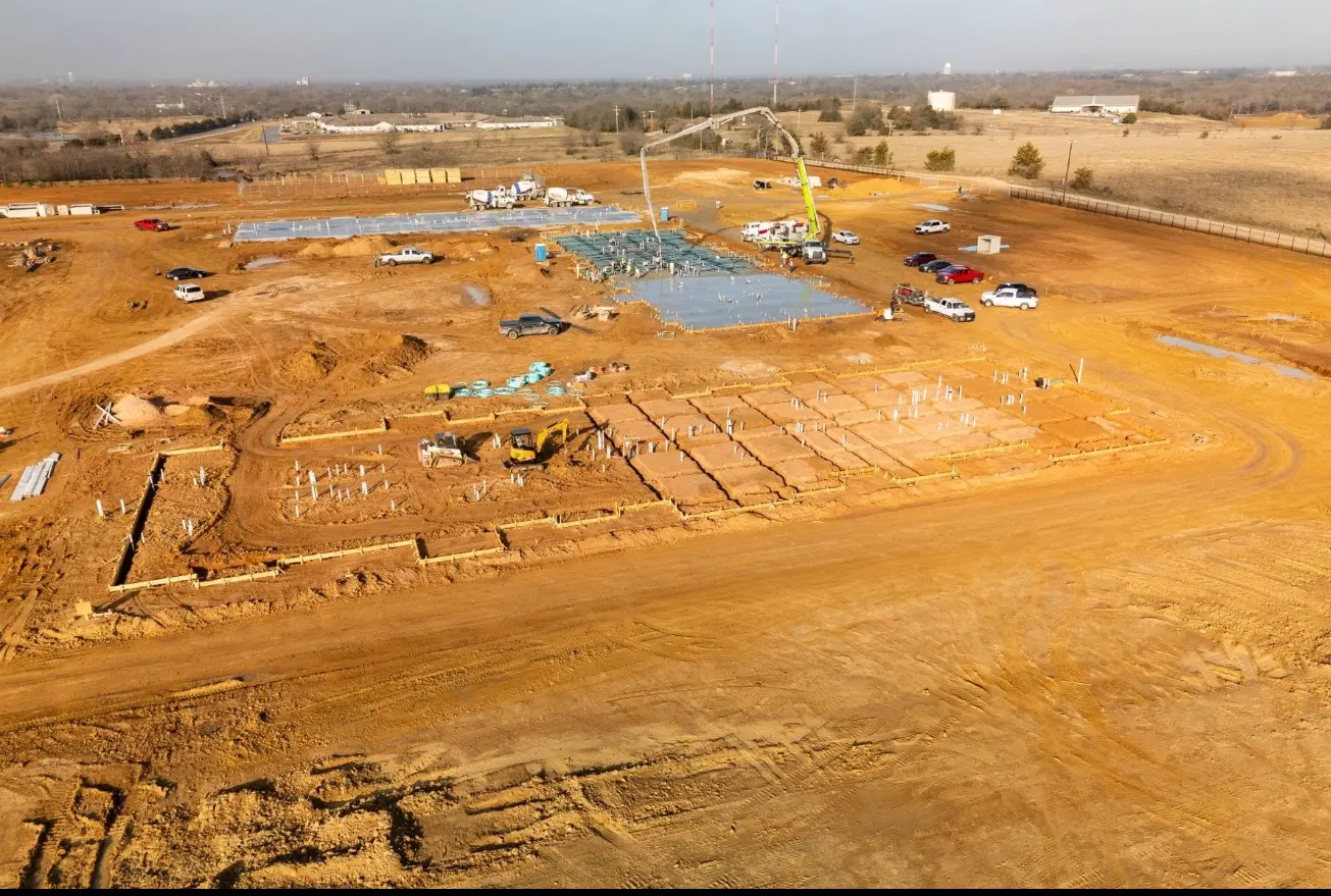 Aerial overview of construction equipment, foundation work and grading at an active development site